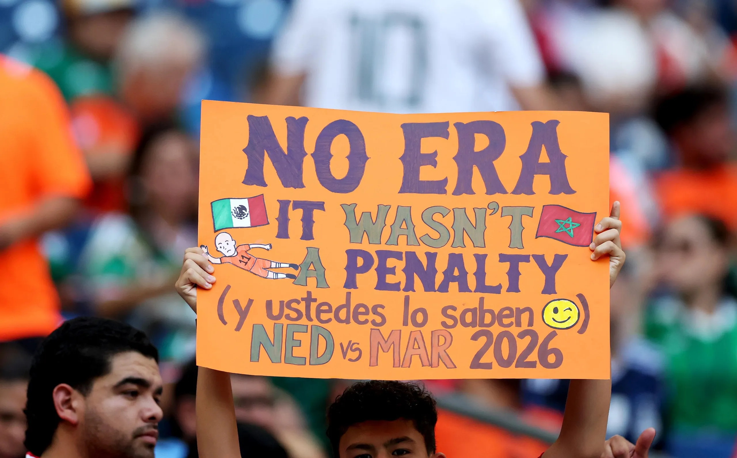 A fan holds a sign that says "No Era It Wasn't a Penalty (y ustedes lo saben)" at Estadio Monterrey.