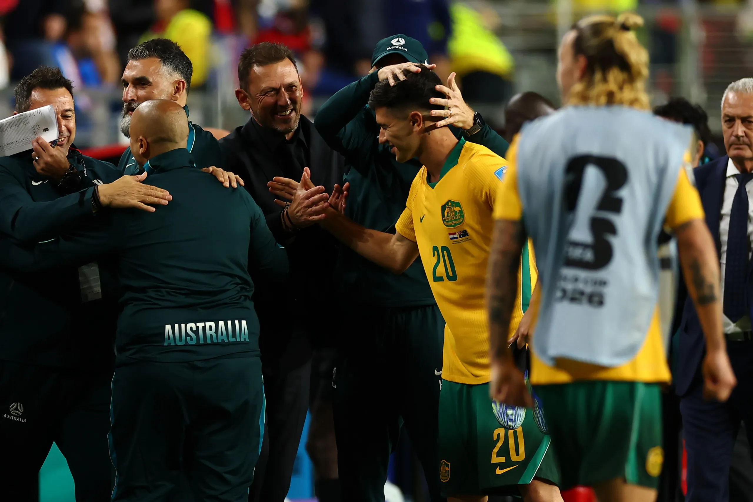 Tony Popovic, the head coach of Australia, celebrates with Cristian Volpato and Jackson Irvine after Australia’s draw against Paraguay.