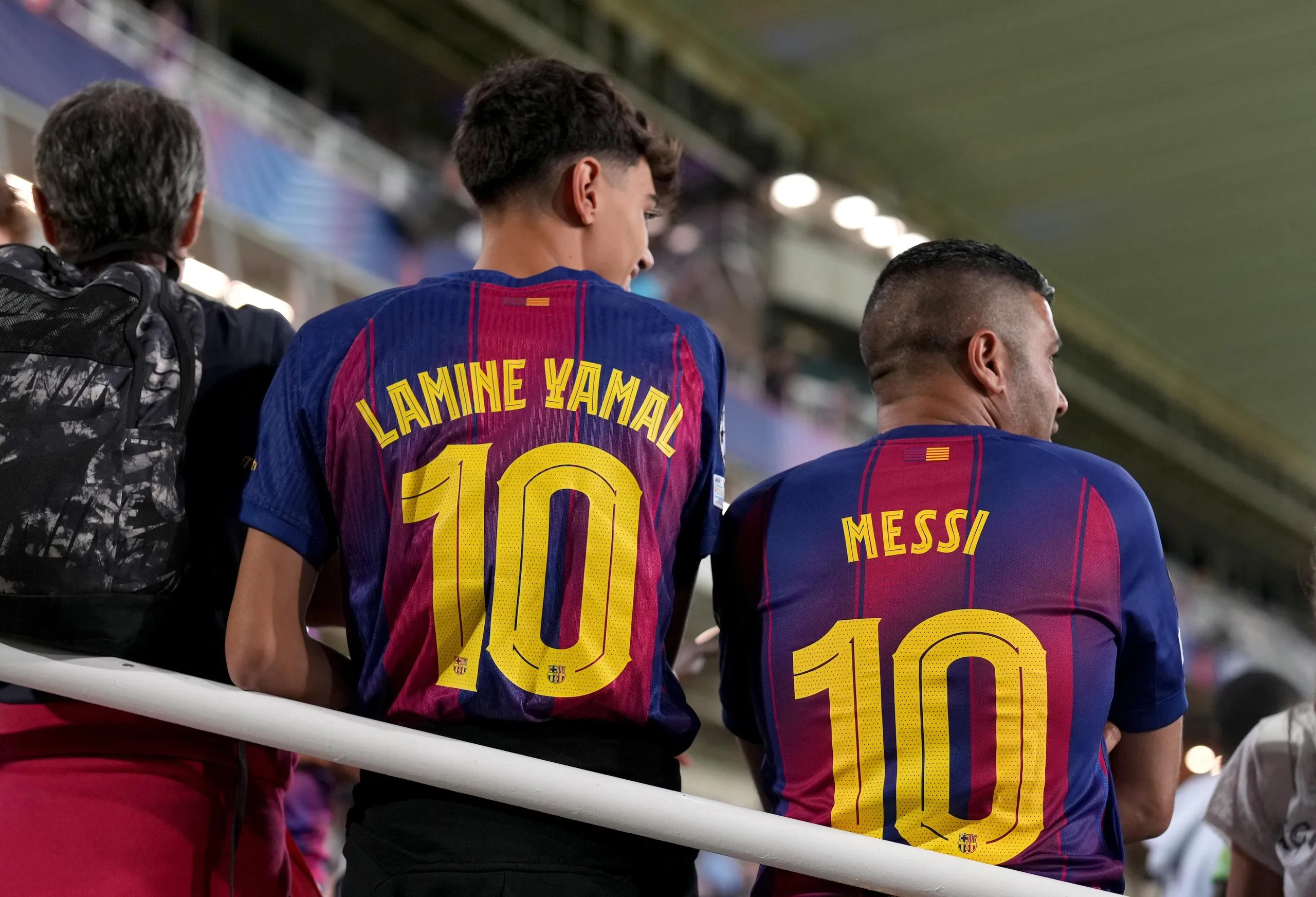 Barcelona fans display the names of Lamine Yamal and Lionel Messi on their shirts