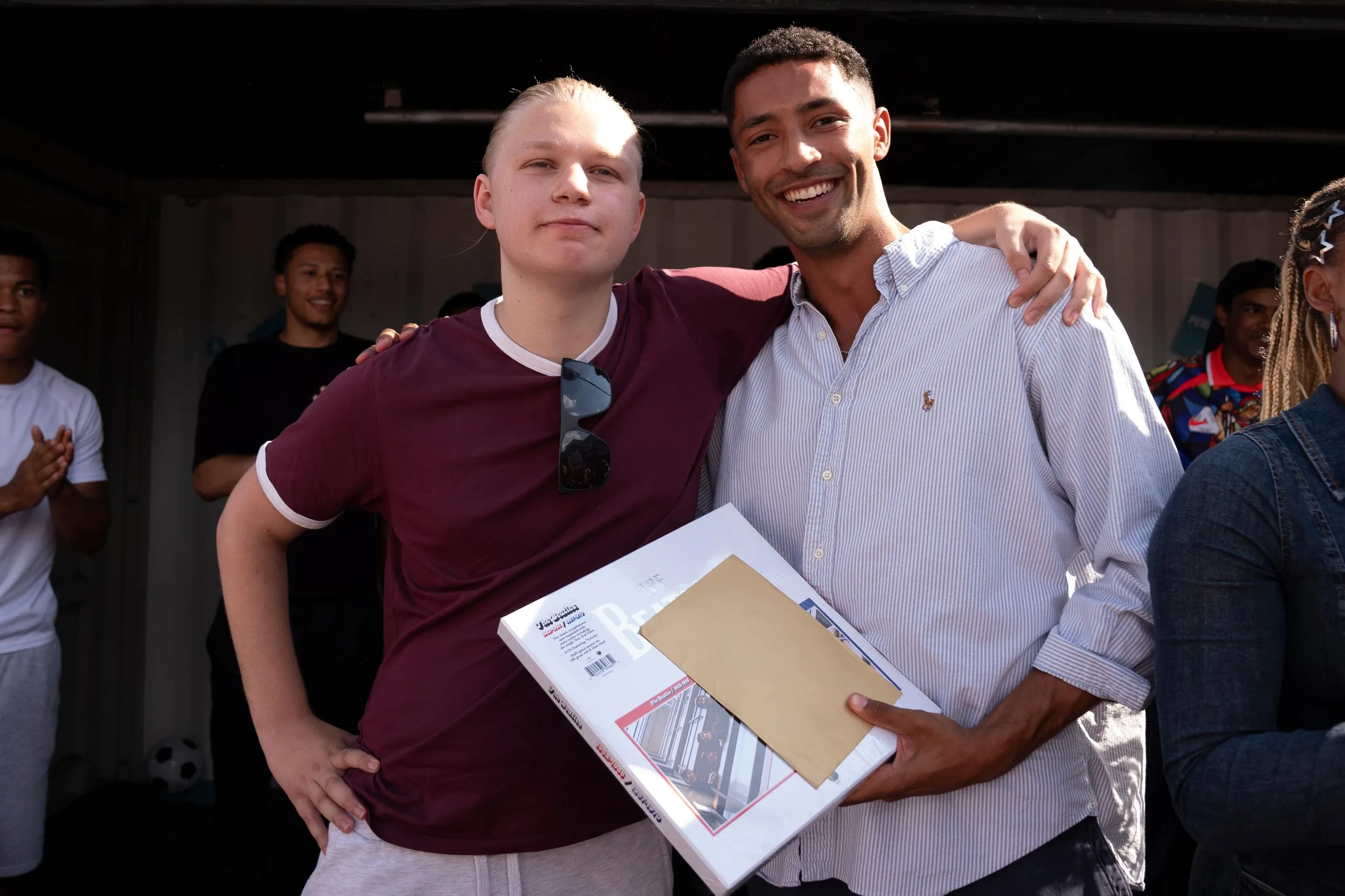Marcus Legemah, the winner of the Jude Bellingham lookalike competition, receives his Deliveroo voucher for £1,966 and a Beatles box-set from an Erling Haaland lookalike